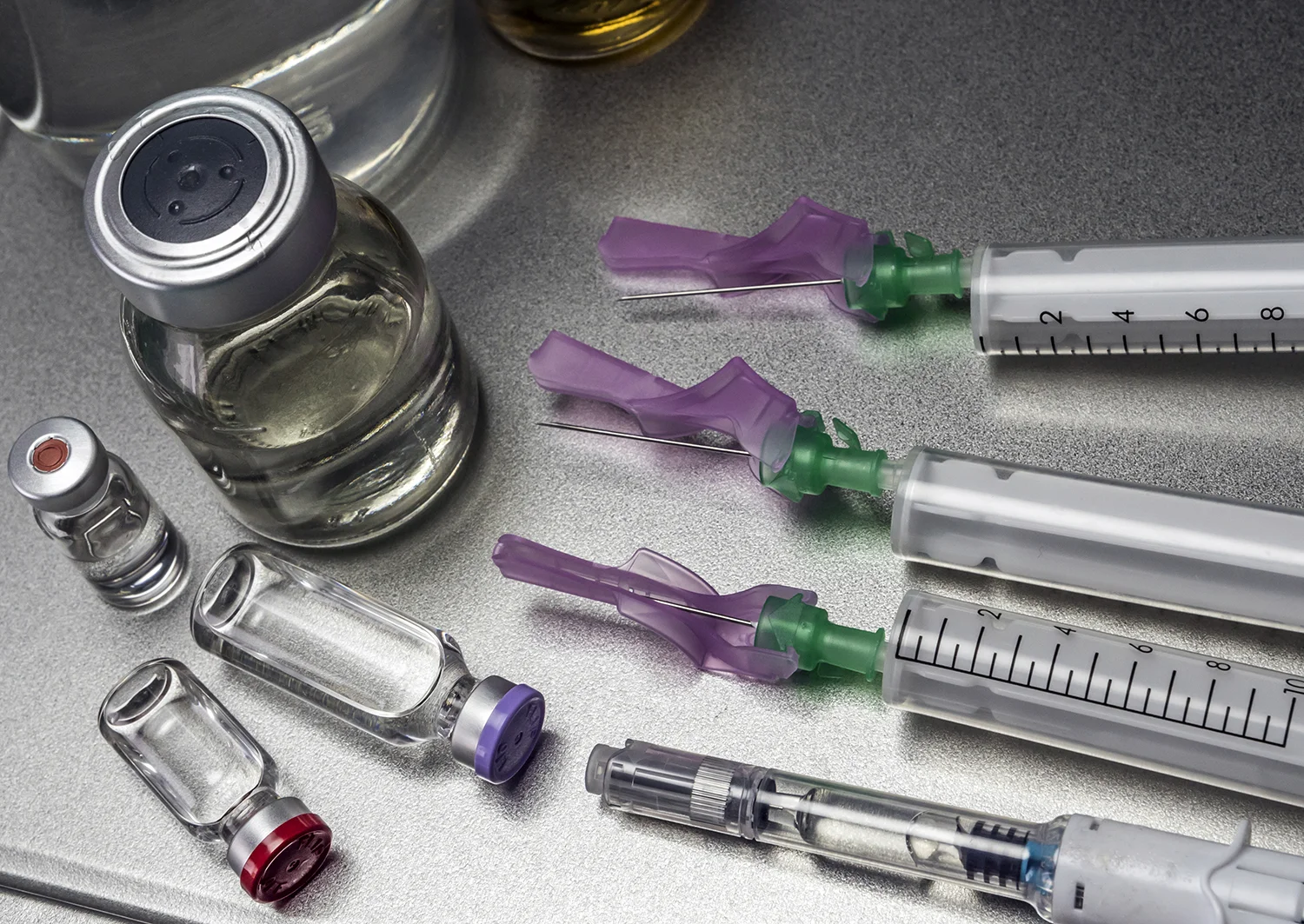 close up of vials and syringes on metal surface